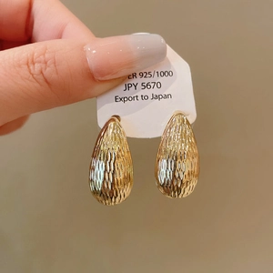 Macro shot of 925 silver gold-plated teardrop earrings with hammered metal texture