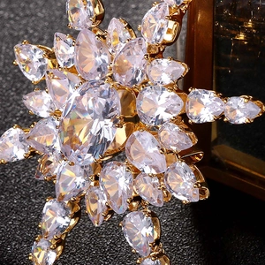 Macro detail of luxury snowflake brooch with sparkling clear zircons on gold metal base