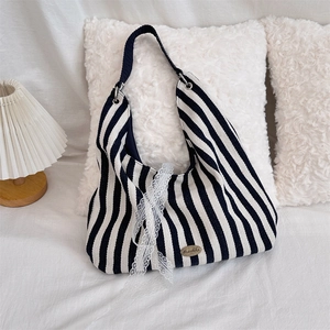 Détail d'un sac cabas en toile à rayures noires et blanches avec un ruban en dentelle