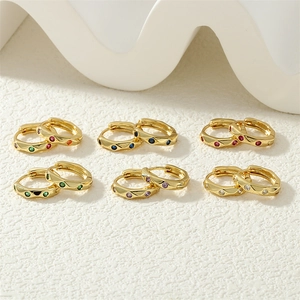 Macro shot of six pairs of gold hoop earrings with colorful inlaid cubic zirconia stones