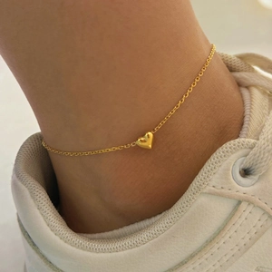 Minimalist gold heart anklet on model ankle with white sneakers shown in natural light
