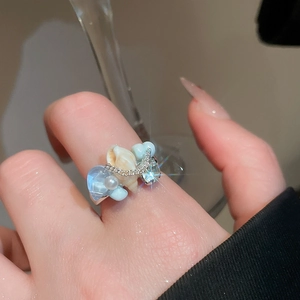 Detail of beaded sea shell ring with light blue heart stone and pearl on a silver band
