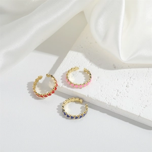 Three adjustable gold heart enamel rings in red, pink, and blue on white silk background