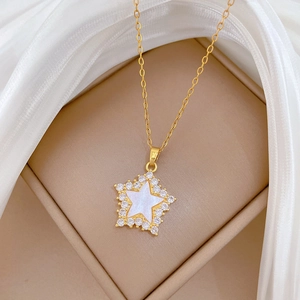 Macro shot of gold star pendant with white shell inlay and pave cubic zirconia