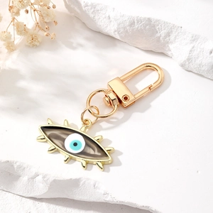 Unique Evil Eye keychain with golden hardware on a white stone and floral background