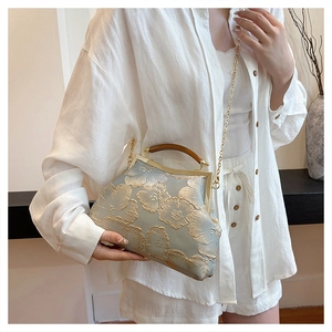 Detail of light blue satin handbag featuring golden floral embroidery and wood handle