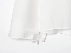 Detailed close-up of the white cotton hem with fine stitching and natural fabric texture