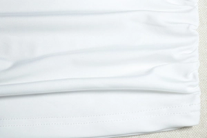 Détail du tissu tricoté blanc avec fronces et finition de l'ourlet à double couture