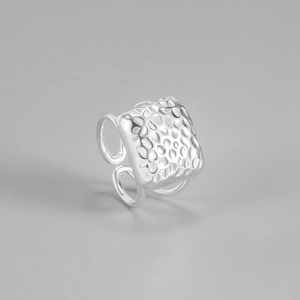 Macro view showing the square hammered texture and adjustable band of the silver ring
