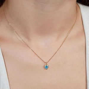 Elegant heart-shaped blue gemstone pendant necklace with golden bead chain on model