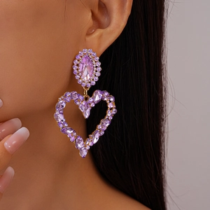 Detail of purple crystal heart drop earrings with gold tone setting on model