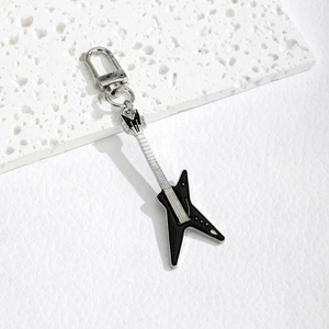 Black and silver electric guitar keychain with lobster clasp on a white stone background