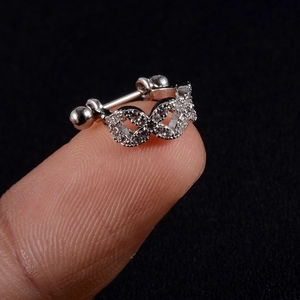 Macro shot of silver zircon studded hinged ear cuff on a fingertip with a black background