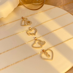 Close-up of gold heart necklaces with infinity symbols and rhinestones on a white plate