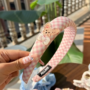 Detail of pink plaid headband with cute cartoon dog and transparent bow decoration