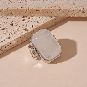 Macro detail of rectangle natural stone ring with silver multi-prong setting on marble