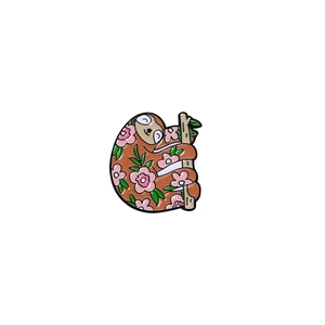 Cute cartoon sloth enamel pin featuring pink flowers and green leaves on a tree branch