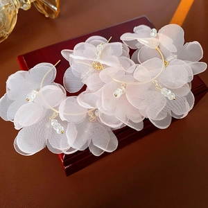Gros plan de boucles d'oreilles fleurs en tulle rose avec créoles dorées et perles fines