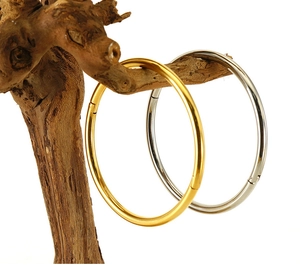 Polished gold and silver stainless steel bangles hanging on a natural wooden branch