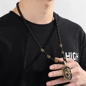 Men's beaded necklace featuring a golden lion head pendant worn by a model in detail