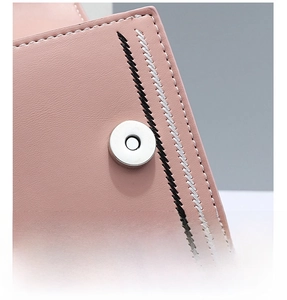 Detailed macro view of pink leather bag featuring magnetic snap closure and contrast stitching
