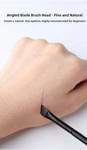 Close-up of angled blade eyeliner brush drawing a thin line on skin for precise makeup