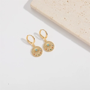 Detailed close-up of gold Evil Eye earrings with colorful crystals on a stone