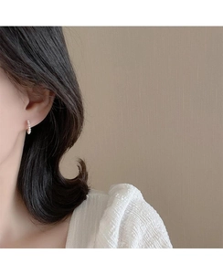 Macro shot of minimalist gold hoop earrings featuring elegant small pearl embellishments