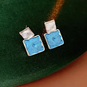Blue and white marble texture square stud earrings with gold plating on green velvet