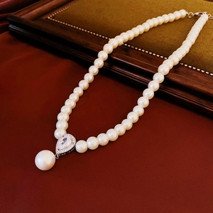 Gros plan d'un collier de perles vintage avec pendentif zircon goutte sur cuir et bois