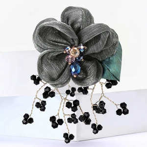 Macro shot of floral lace brooch with colorful crystal beads and black tassel details