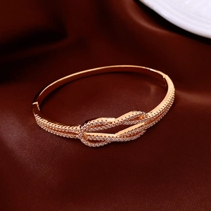 Détail du bracelet noeud plaqué or 18 carats orné de strass étincelants sur soie rouge