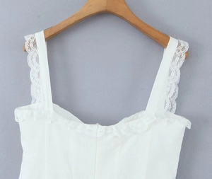 Detailed close-up of white camisole top with delicate lace trim on wooden hanger