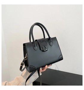 Detail of black crossbody bag with crocodile texture corners and metal twist lock