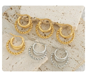 Detailed macro view of gold and silver twisted cable hoop earrings on a stone plate