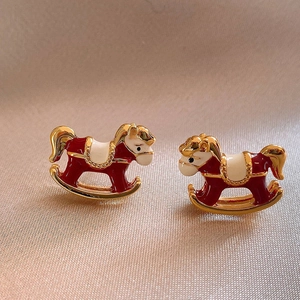 Détail de boucles d'oreilles cheval à bascule en émail rouge avec bordure dorée chic