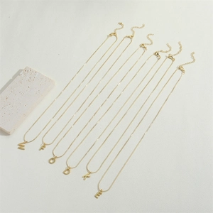 Macro detail of 14K gold plated letter pendants M F O D K E on delicate chain necklaces