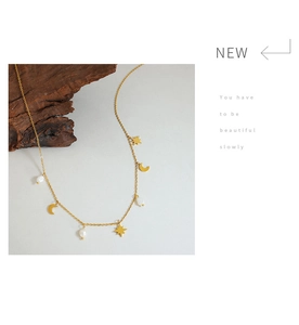 Detail of star and moon charms with freshwater pearls on a gold tassel necklace