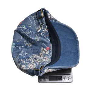 Detail shot of vintage denim flat cap showing floral pattern and weight of 84.5g on scale