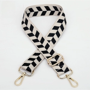 Detail of adjustable black and white chevron jacquard bag strap with gold metal hooks