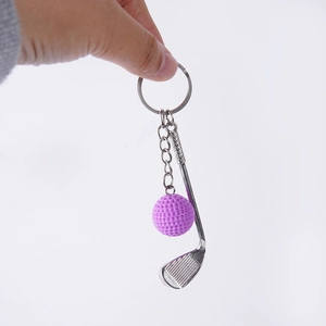 Silver metal golf club and purple ball keychain charm displayed on white background
