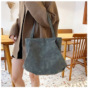 Close-up of geometric dark grey tote bag featuring matte suede texture and side folds