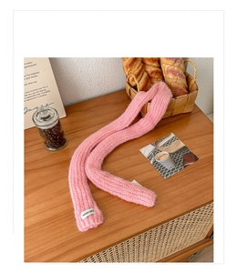 Detail of pink knit scarf with vegetable label on a rustic wooden table setting