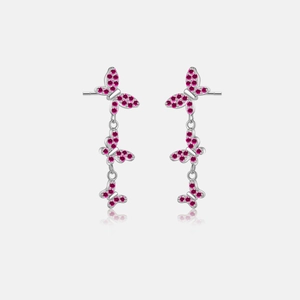 Macro shot of silver butterfly drop earrings with shimmering rose red zircon pave setting