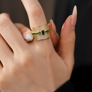 Close-up of gold ring with emerald-cut green stone and pavé zircon on model hand