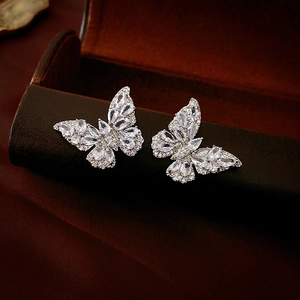 Macro shot of silver butterfly stud earrings with sparkling cubic zirconia on leather box