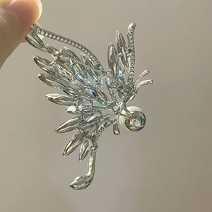 Gros plan détaillé d'une broche papillon en argent avec zircons et une grande perle ronde