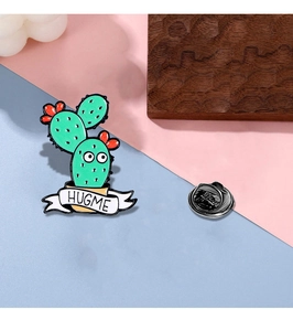 Close-up of a cute cactus enamel pin with HUGME text and a butterfly clutch back