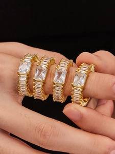 Detailed view of stacked gold geometric rings featuring large rectangular zircons on fingers