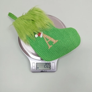 Detailed close-up of a green knit Christmas stocking with gold letter A and weight display